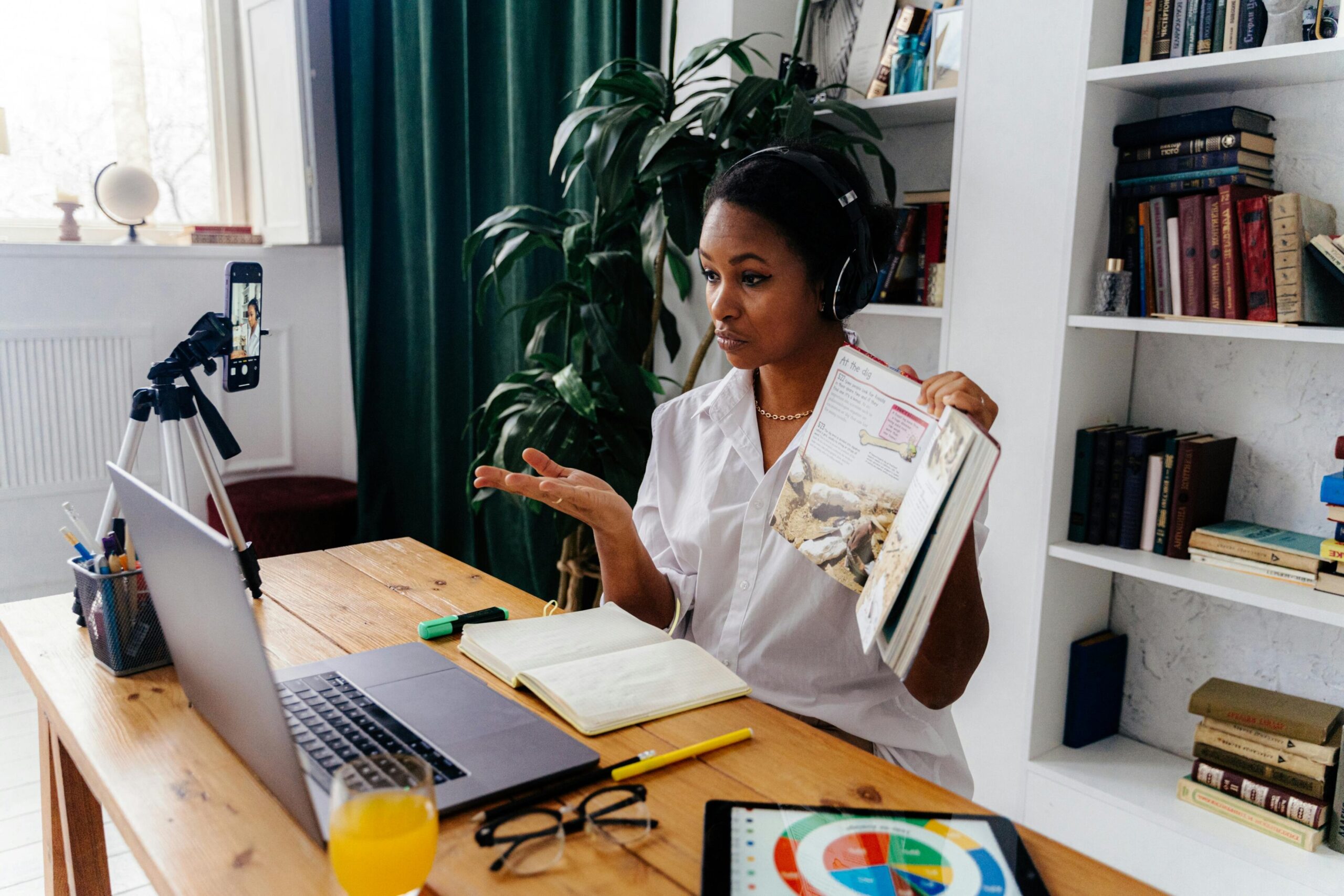 Woman conducting online teaching session at home with laptop and books.